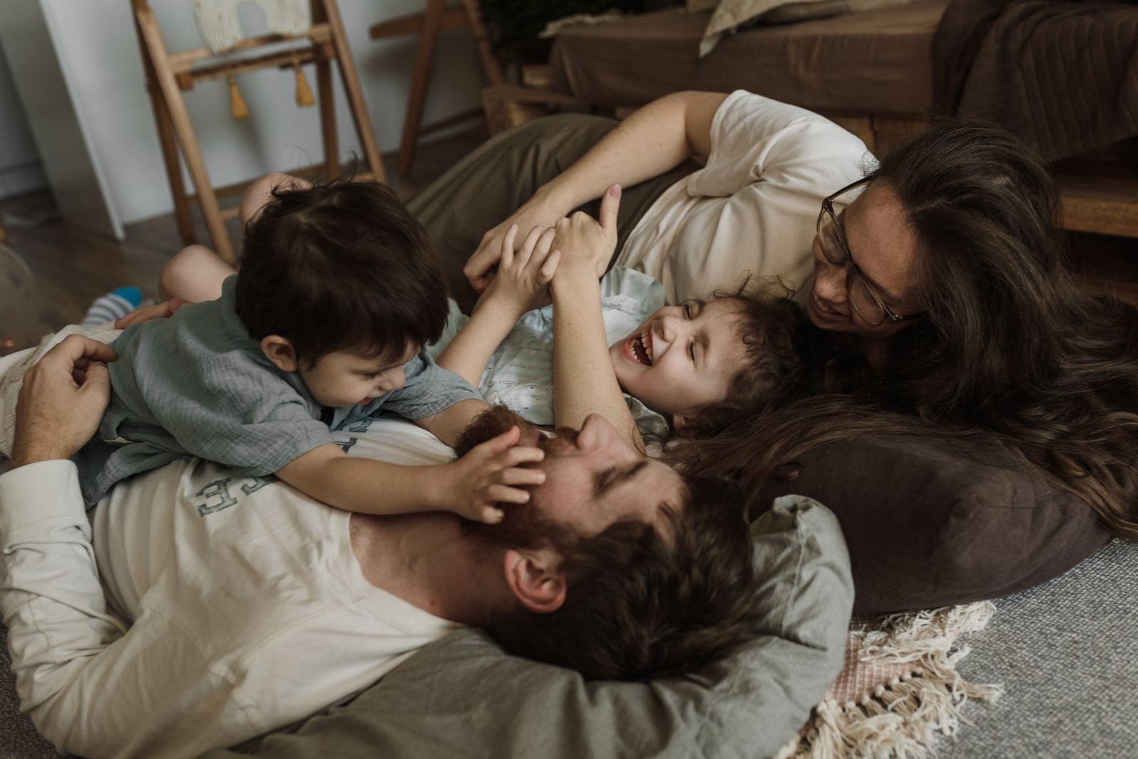 A joyful family of four relaxing indoors, sharing laughter and affection.