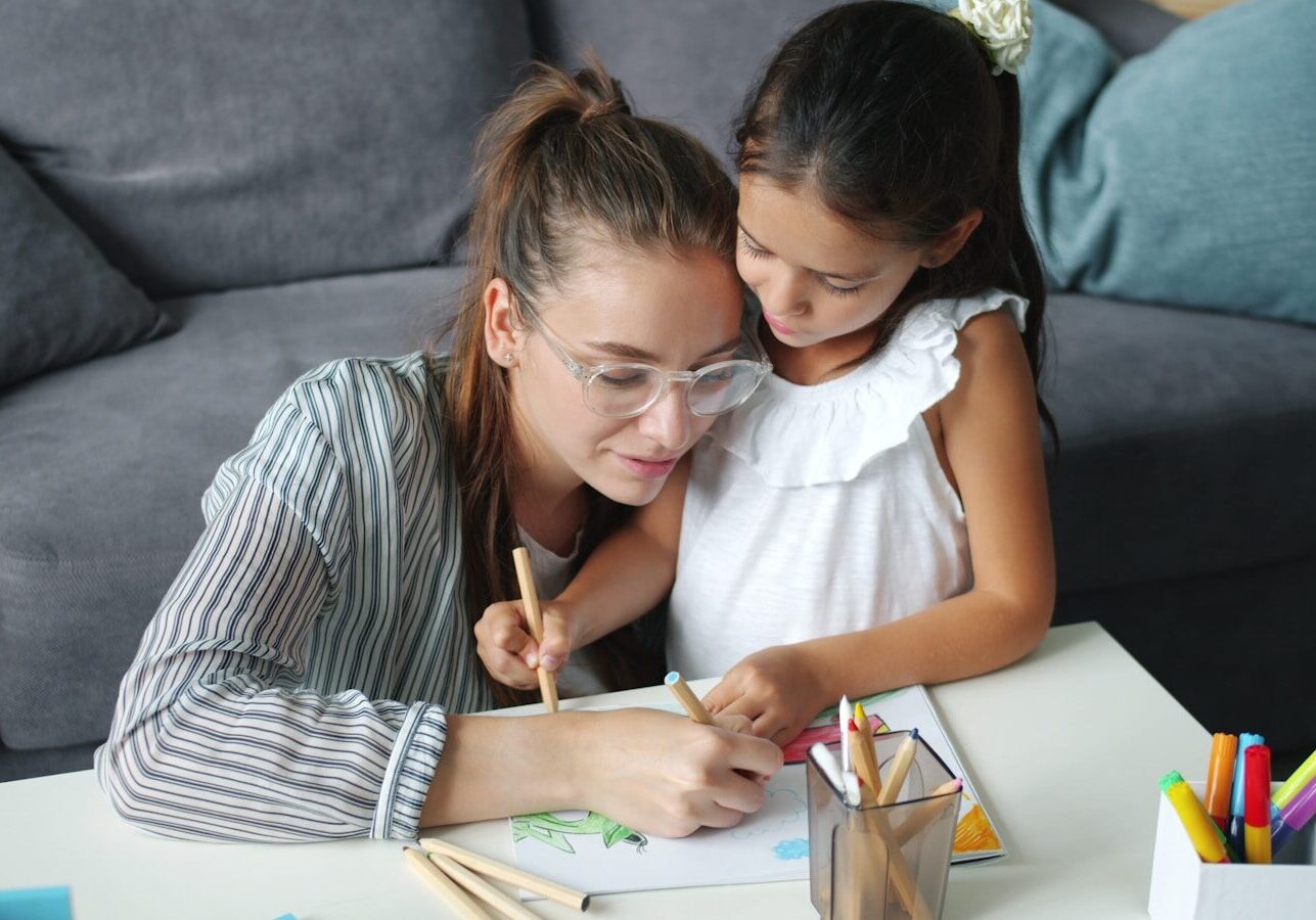 Mother and daughter drawing together at a table.